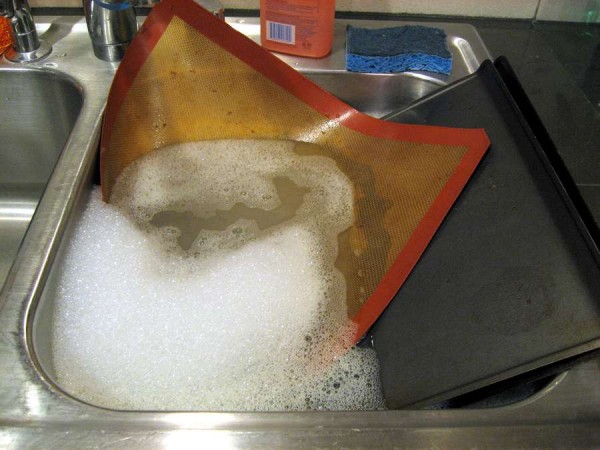 Kitchen sink with silpat and baking sheet in it.